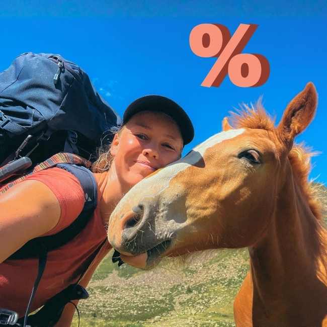 Frau mit einem Pferd mit Prozent-Zeichen im Hintergrund