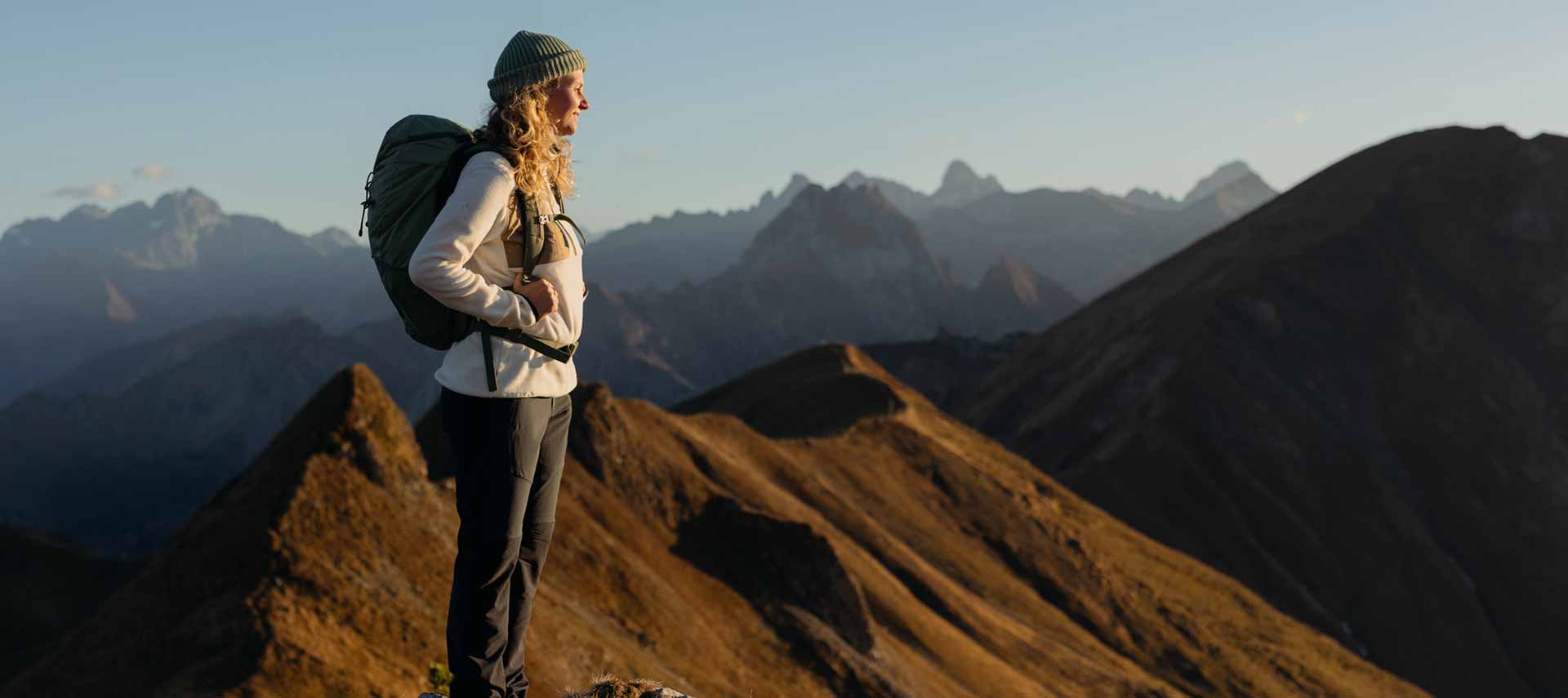 Rethink-Kollektion entdecken Frau steht auf Berggipfel und blickt in die Ferne