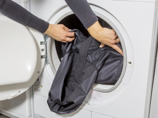 Eine Jacke wird in eine Waschmaschine gelegt