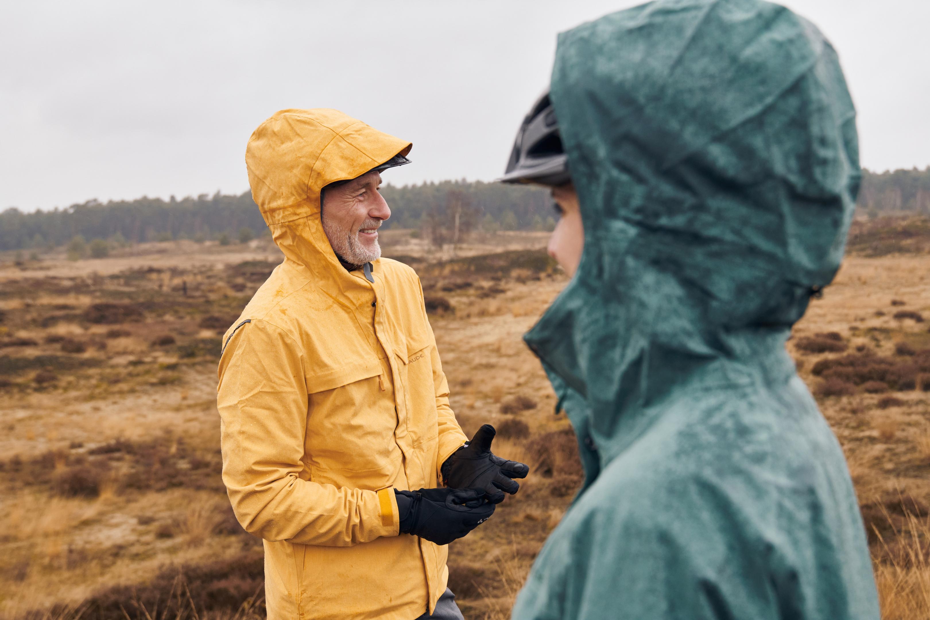 Mann und Frau mit Regenjacke und Kapuze auf dem Kopf bei regnerischem Herbstwetter