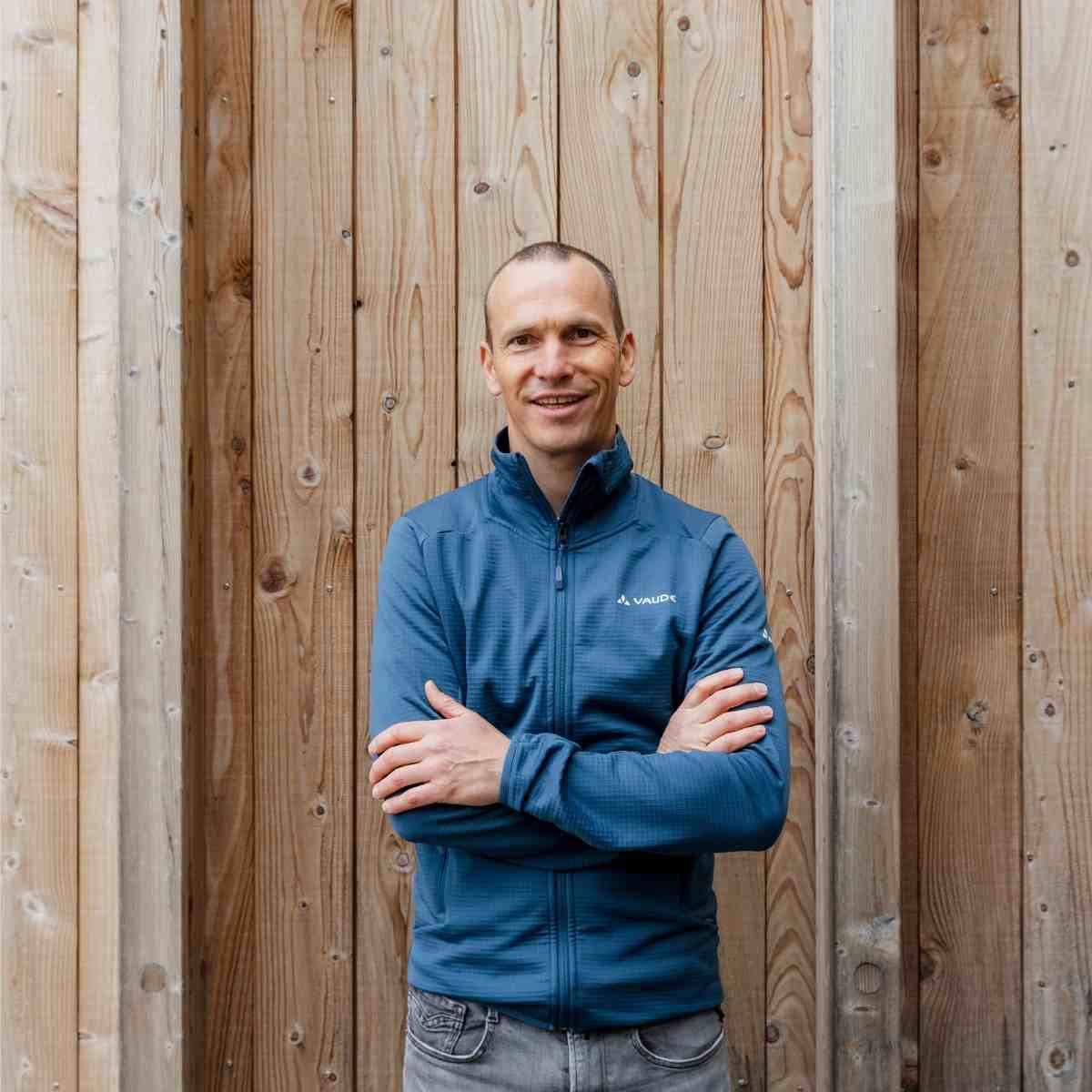 Michael, Mitarbeiter von VAUDE Michael, Mitarbeiter von VAUDE, steht vor einer Natur-Holzwand